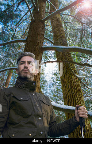 Caucasian hiker holding walking stick under snowy tree Stock Photo