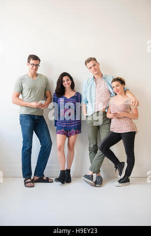 Portrait of smiling Caucasian friends leaning on wall Stock Photo