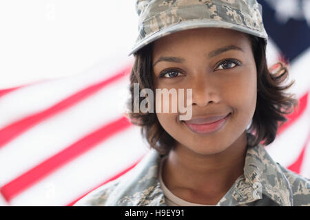 Portrait of smiling Mixed Race soldier near American flag Stock Photo