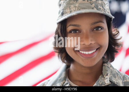 Portrait of smiling Mixed Race soldier near American flag Stock Photo