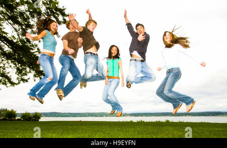 Friends jumping for joy near river Stock Photo