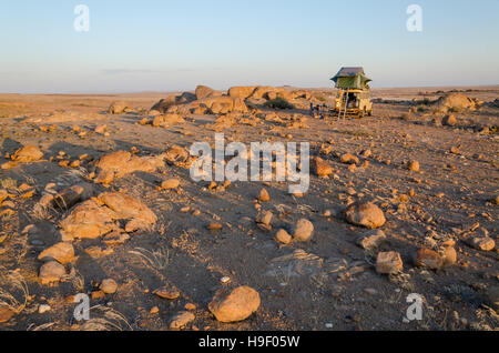 Camping with a 4x4 and roof top tent in a rocky part of Angola's Namib Desert. Stock Photo