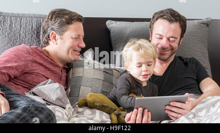 Caucasian fathers using digital tablet on bed with son Stock Photo