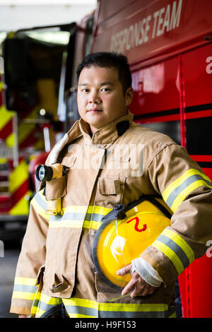 Serious Chinese fireman standing near fire truck Stock Photo