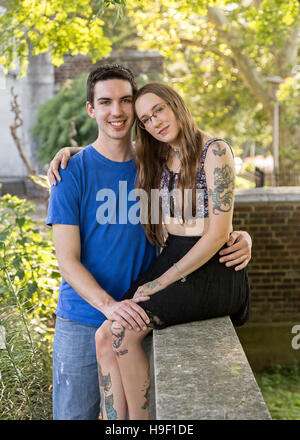 Caucasian couple posing on wall at park Stock Photo