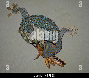 Tokay gecko, Gekko gecko, with recently caught cricket on a wall in Bali, Indonesia Stock Photo