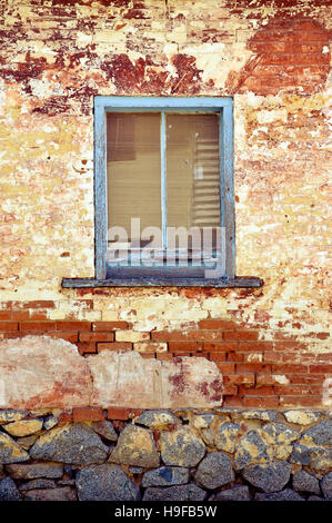 Rustic old blue wooden window frame on historic building. Distressed rendered brick wall. Stock Photo