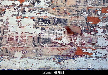 Old layers of colorful peeling paint on exterior brick, wall of a historic building. Textured background. Stock Photo