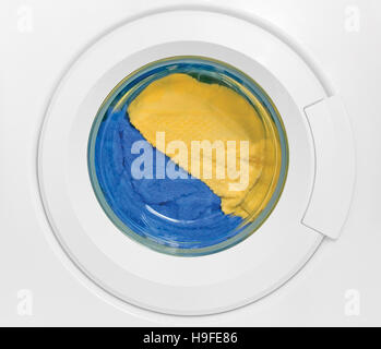 Washing machine door, clean colorful clothes, yellow, blue plush terry closeup Stock Photo