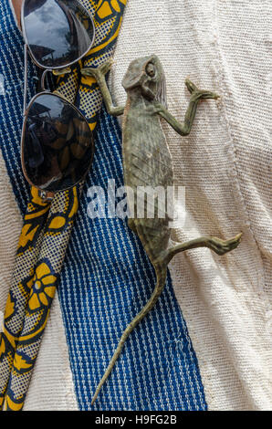 Little green chameleon climbing up shirt next to sunglasses Stock Photo