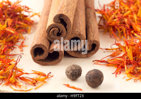 Cinnamon sticks, aromatic saffron and pimento on yellow wooden tray close-up with shallow depth of focus. Stock Photo