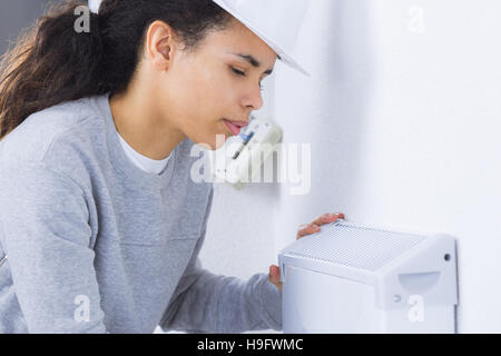 Female worker fitting appliance to wall Stock Photo