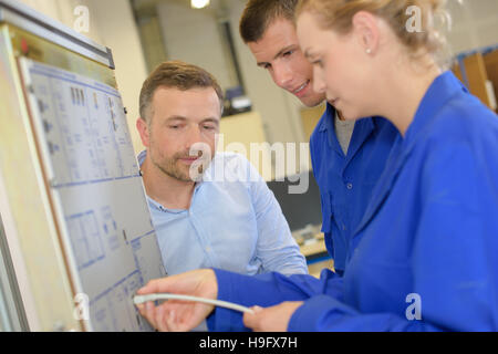 engineer working with apprentices on factory floor Stock Photo
