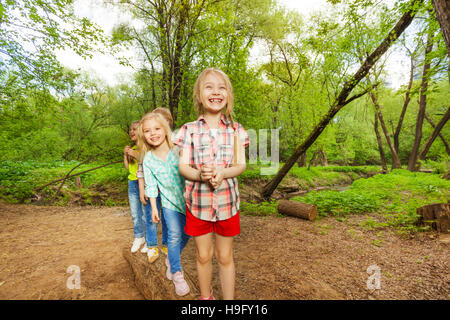 Kids standing on a log one after another in forest Stock Photo