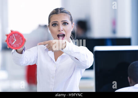 Businesswoman with clock being late for her deliverables Stock Photo