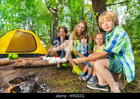 Happy family roasting marshmallows in the woods Stock Photo