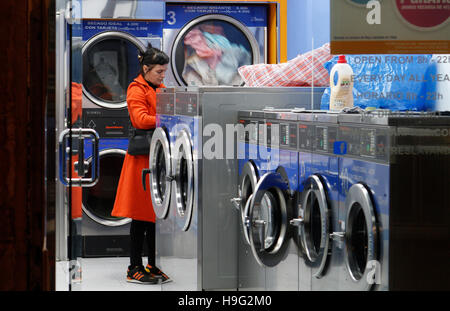 Woman in a laundromat waiting for her clothes. Stock Photo