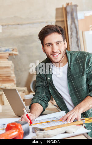 Carpenter with floorplan at workbench Stock Photo