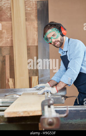 Carpenter cutting wood using protection Stock Photo