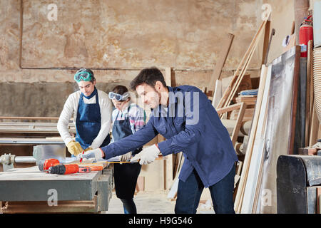 Carpenter in apprenticeship at carpentry shop during measuring lesson Stock Photo