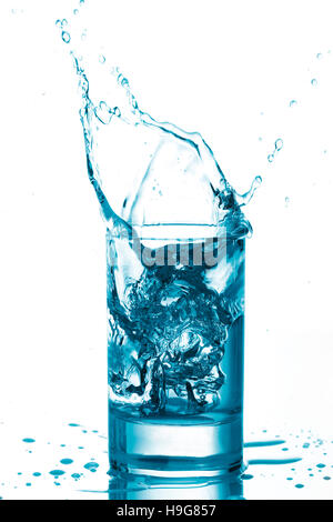 Ice cube dropping into water glass Stock Photo