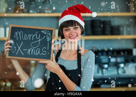 Composite image of portrait of waitress showing slate with merry x-mas text Stock Photo