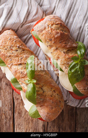 Italian sandwiches with fresh tomatoes, mozzarella cheese and basil close-up on the table. vertical view from above Stock Photo