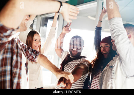 Ecstatic friends or co-workers raising hands in triumph Stock Photo
