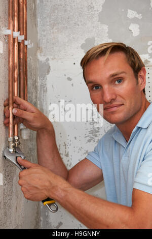 Plumber Working On Pipes At Construction Site Stock Photo