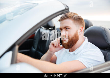 Handsome young man driving his car and speaking on the cellphone Stock Photo