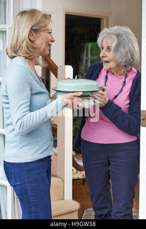 Woman Bringing Meal For Elderly Neighbour Stock Photo