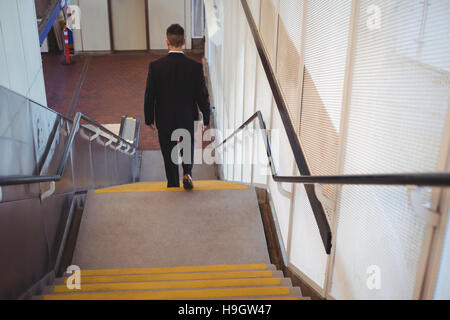 Businessman with a diary walking down stairs Stock Photo