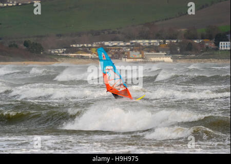 Weymouth, Dorset, UK.  24th November 2016.  UK Weather.  A view towards Bowleaze across a sea of white horses on the waves ar whipped up by strong winds and choppy seas at Weymouth Beach in Dorset which a windsurfer is taking full advantage of.  Photo by Graham Hunt/Alamy Live News Stock Photo