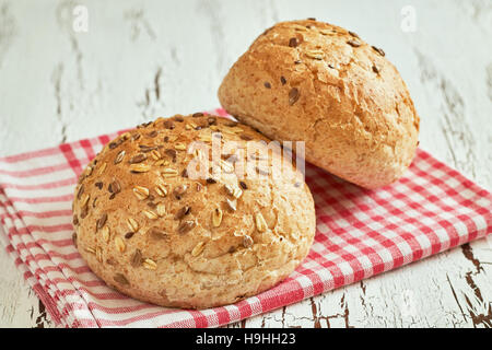 Whole wheat buns with mixed seeds on white rustic wooden background Stock Photo