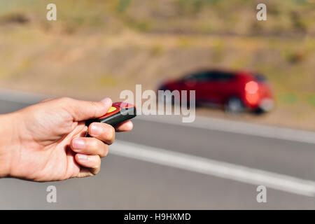 closeup of a young caucasian man opening or closing his car with the control remote key parked next to the road Stock Photo
