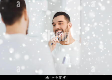 man with toothbrush cleaning teeth at bathroom Stock Photo