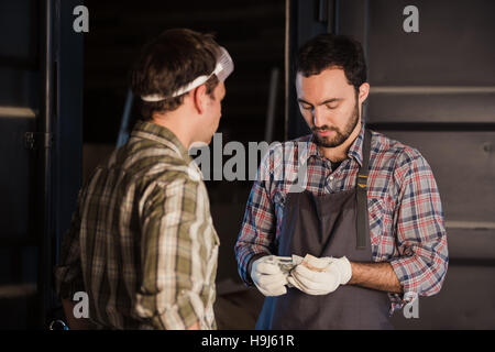 Young carpenter gets money for his work in workshop carpentry Stock Photo