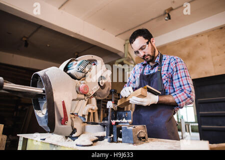 Young craftsman in uniform working at carpentry Stock Photo