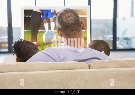 Composite image of two children sitting on sofa with their father Stock Photo