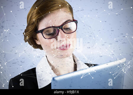 Composite image of redhead businesswoman using her tablet pc Stock Photo