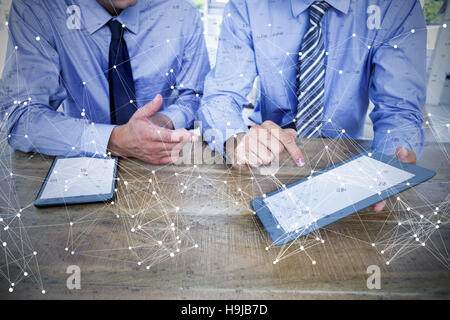 Composite image of businessmen using digital tablet at table Stock Photo