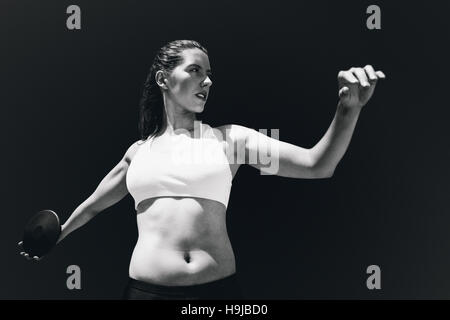 Composite image of front view of sportswoman practising discus throw Stock Photo