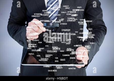 Composite image of businessman looking at tablet with magnifying glass Stock Photo