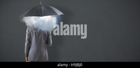 Composite image of businessman standing under umbrella Stock Photo