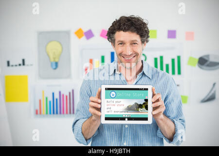 Composite image of businessman showing digital tablet with blank screen in creative office Stock Photo