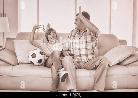 Father and son giving high-five while watching soccer match Stock Photo
