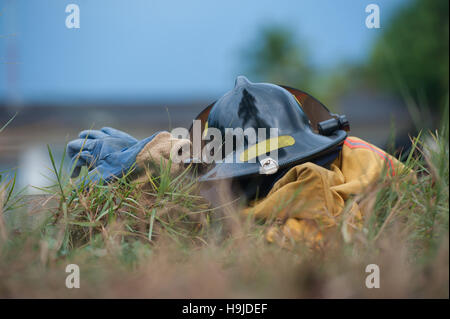 Heavy Duty Protective Fire Fighting Cloth, Gloves, Helmet, Jacket, Pants, on Green Grass Background Stock Photo