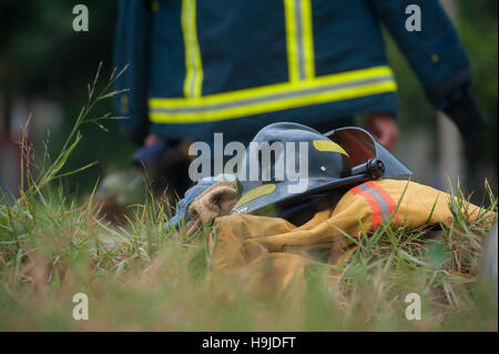 Heavy Duty Protective Fire Fighting Cloth, Gloves, Helmet, Jacket, Pants, on Green Grass Background Stock Photo