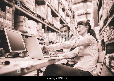Warehouse worker and manager looking at laptop Stock Photo
