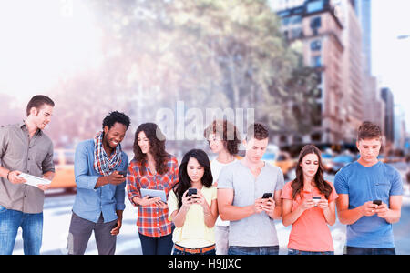 Composite image of four people standing beside each other and texting on their phones Stock Photo